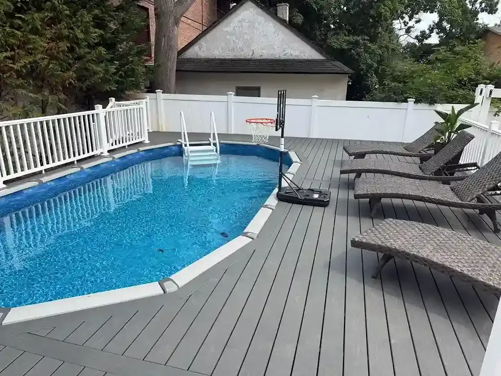 Backyard with composite deck, above-ground pool and white fence