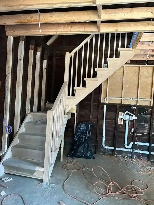 Basement staircase framing with new wood stairs and exposed studs