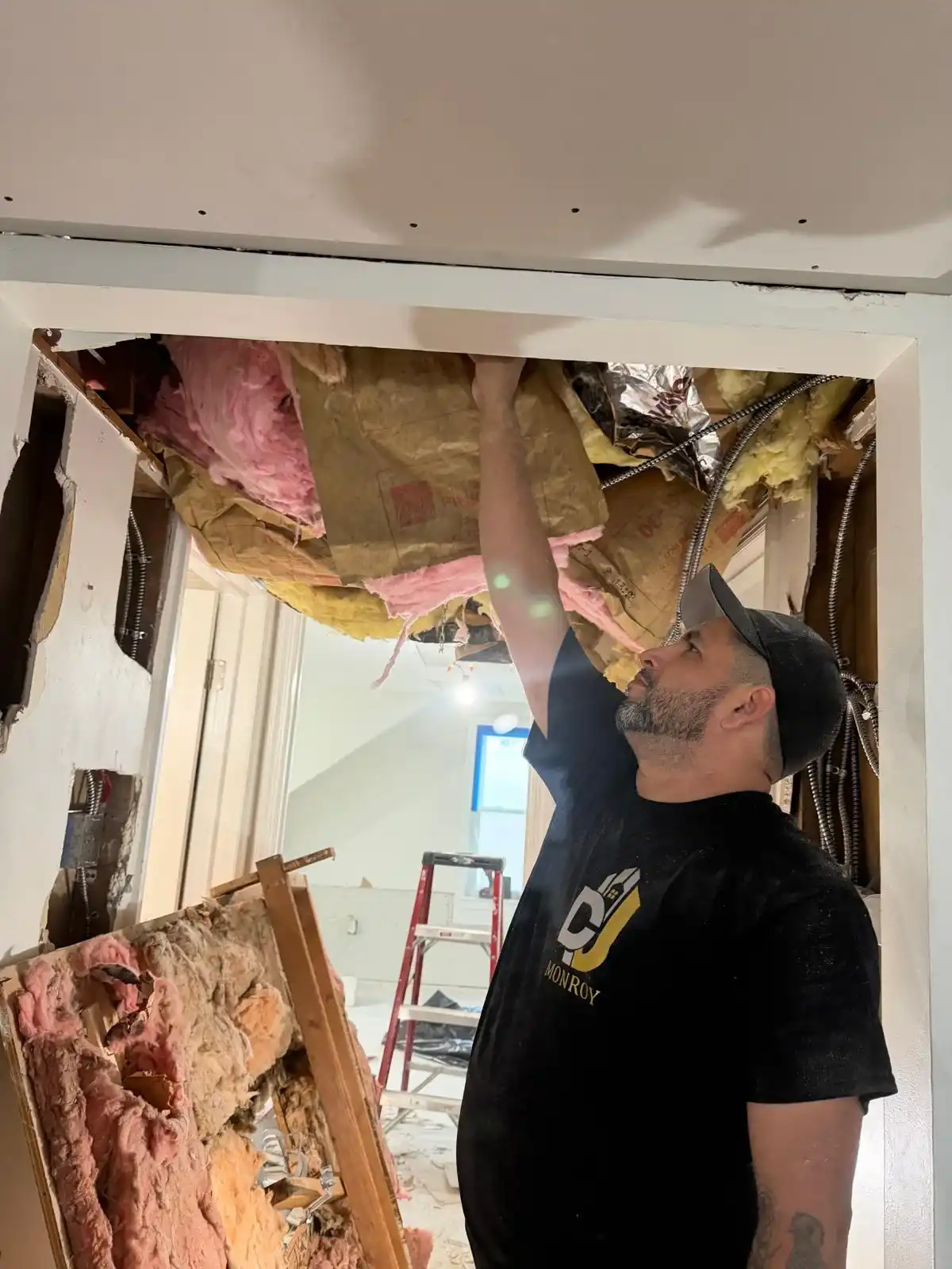 Contractor removing exposed insulation during interior ceiling demolition in Brooklyn renovation