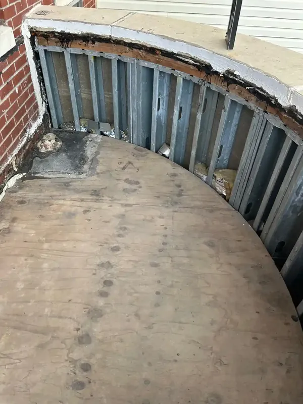 Curved balcony framing with metal studs and plywood during exterior renovation