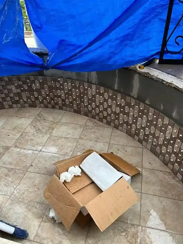 Curved balcony tiled floor under construction with mosaic border and tarp