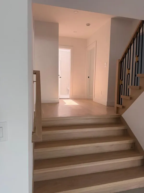 Finished interior staircase with light wood treads and black metal railing