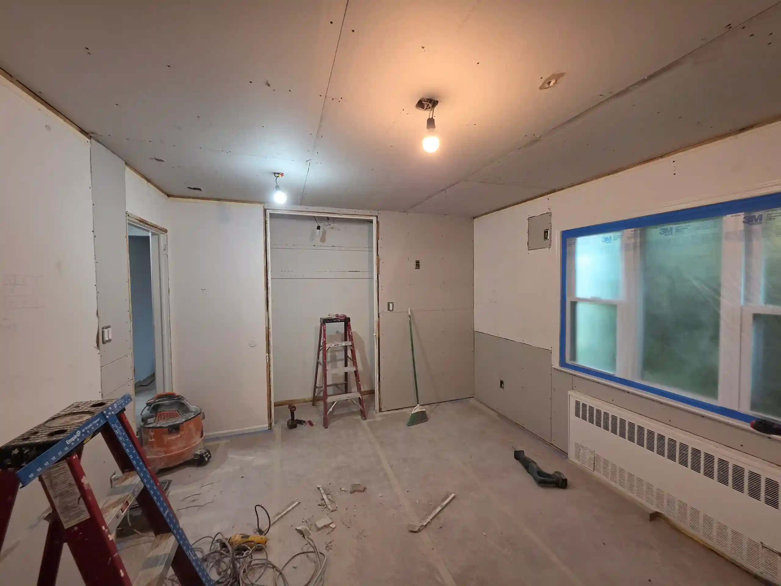 Interior home renovation in progress with drywall installation and exposed ceiling