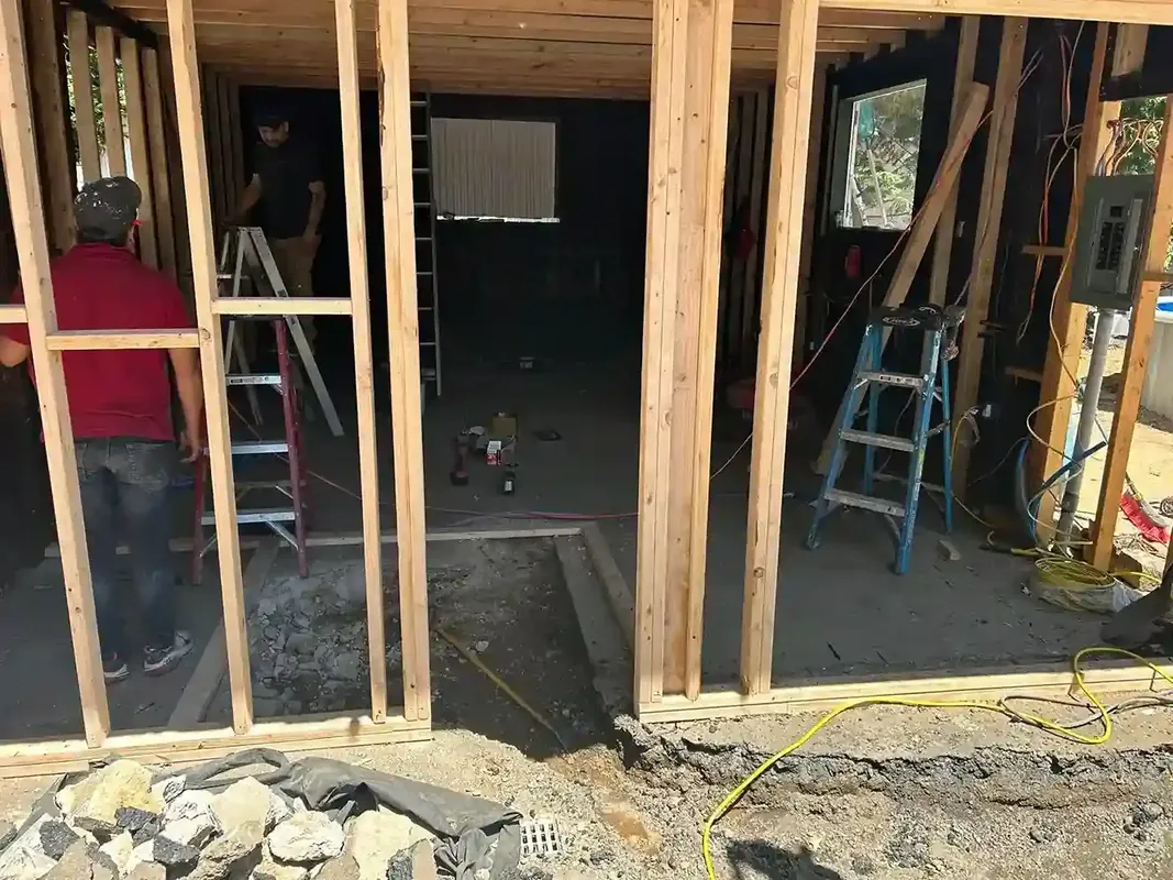 Interior wood framing during home renovation with ladders and concrete floor
