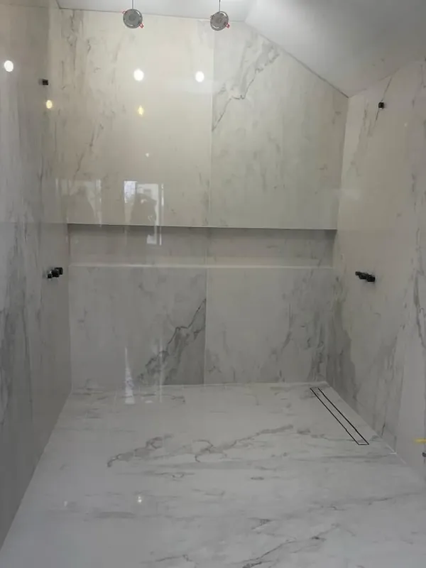 Marble-look tiled shower stall with niche and linear drain renovation