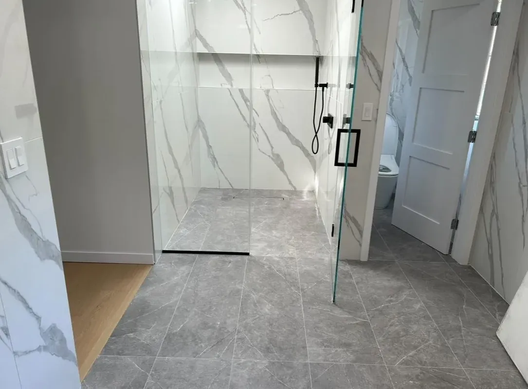 Modern bathroom with glass walk-in shower and marble-look tile in Brooklyn