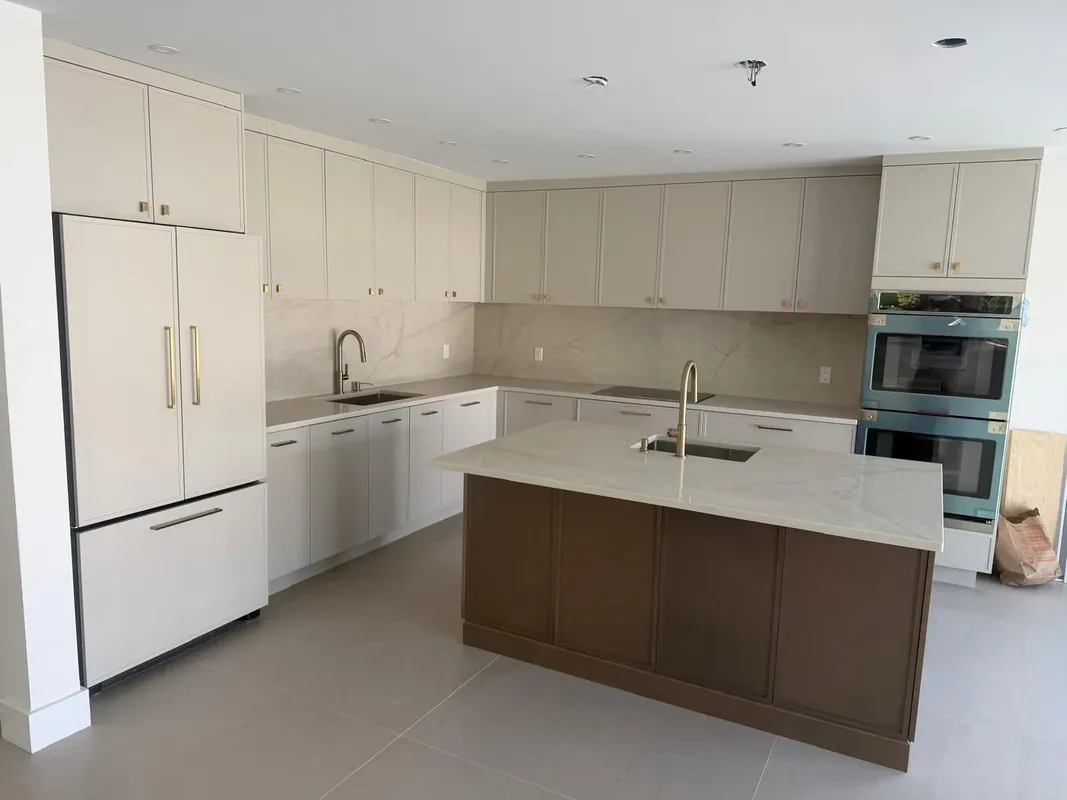 Modern white kitchen with marble backsplash, island and stainless appliances