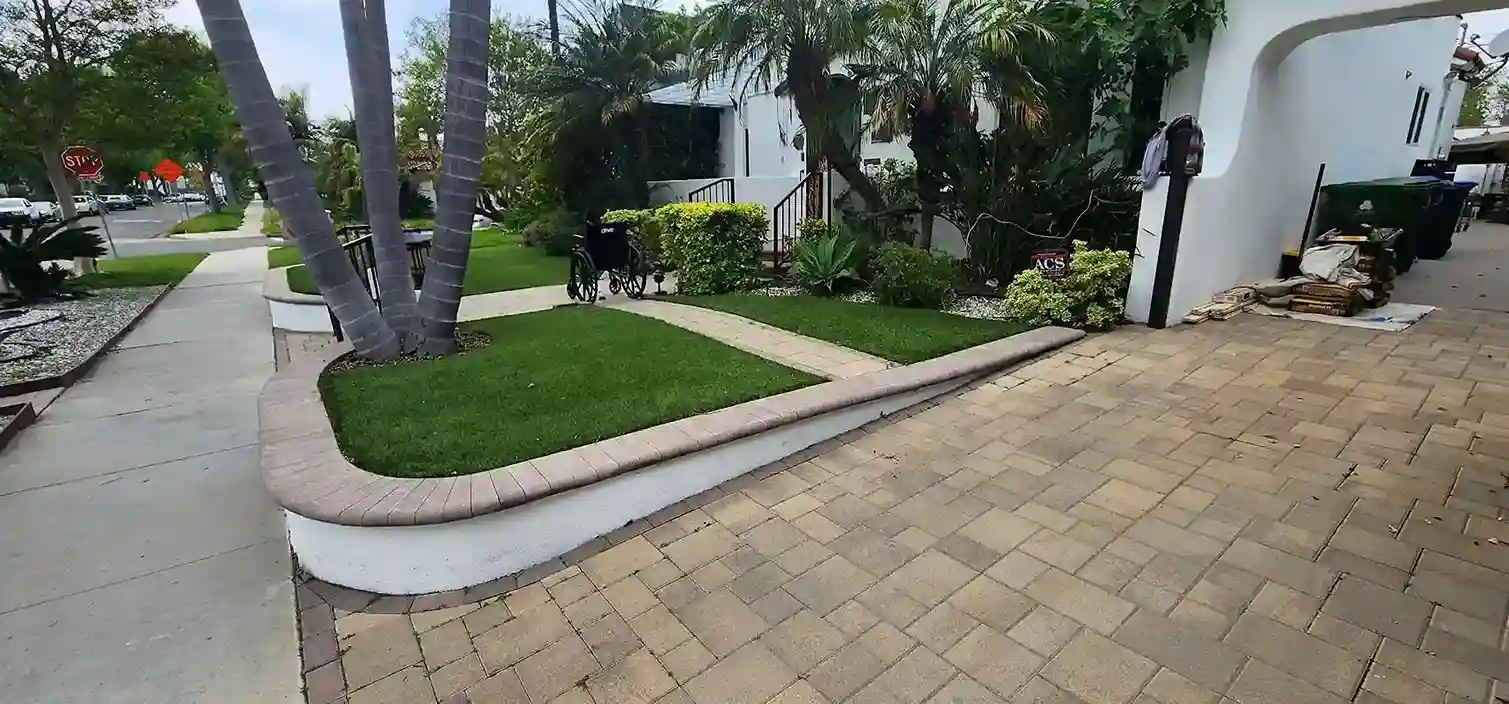 Paver driveway and curved retaining wall with fresh green lawn landscaping in Brooklyn NY
