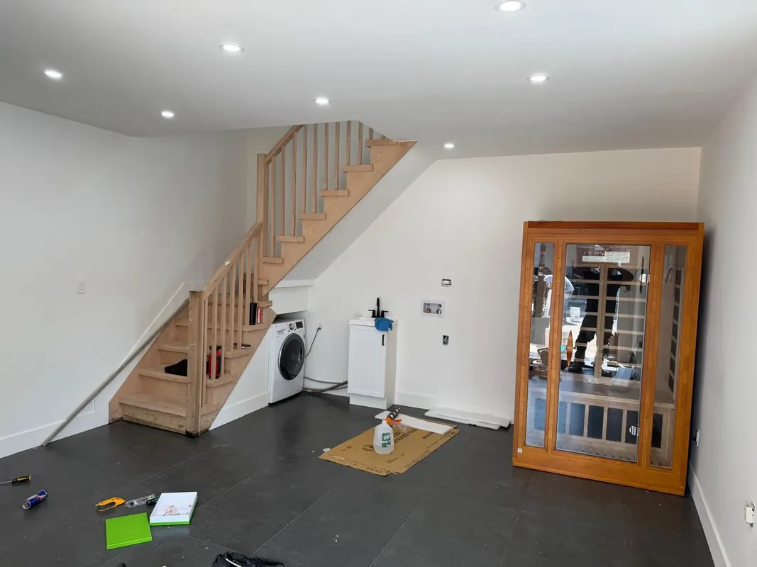 Renovated basement with wood staircase, dark tile floor and glass cabinet