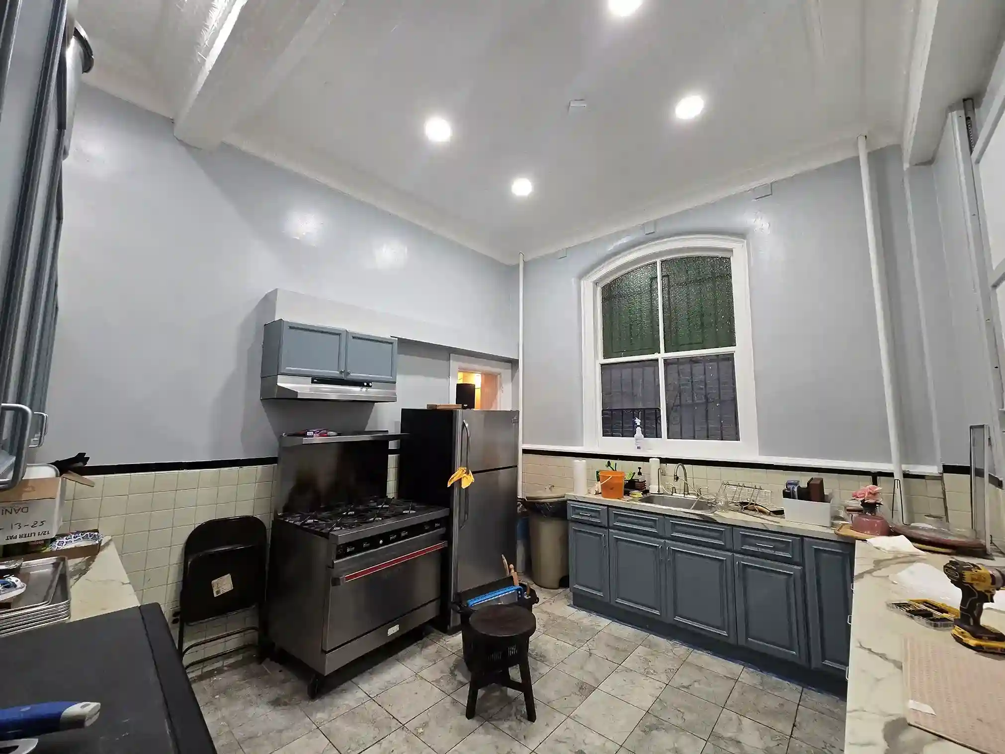 Renovated galley kitchen with gray cabinets, stainless steel appliances and marble tile flooring in Brooklyn home