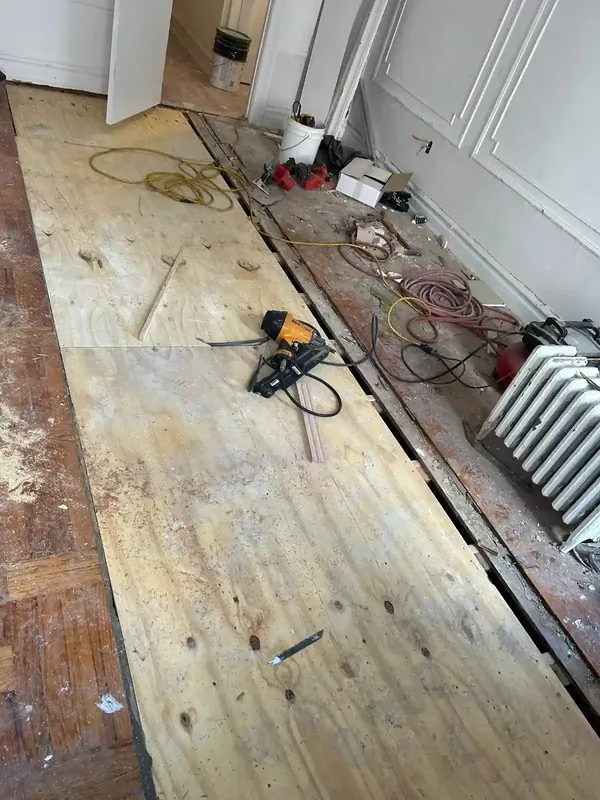 Subfloor plywood installation in progress with drill and tools